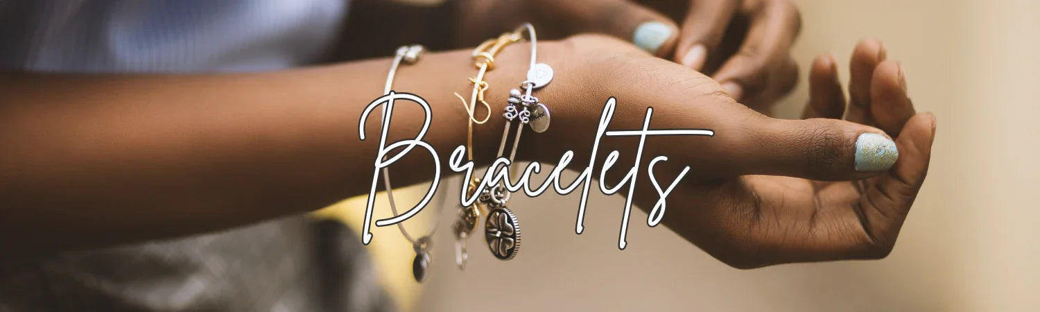 Close-up of a wrist with several charm bracelets and a hand with glittery nail polish