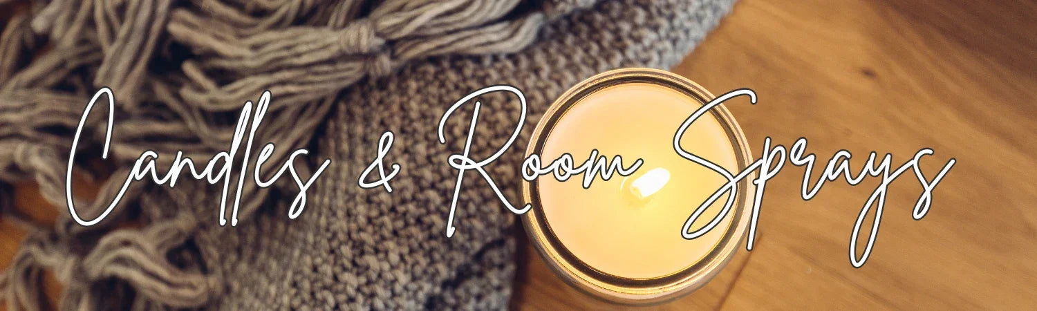 Lit candle on wooden surface beside cozy knit blanket and text Candles & Room Sprays